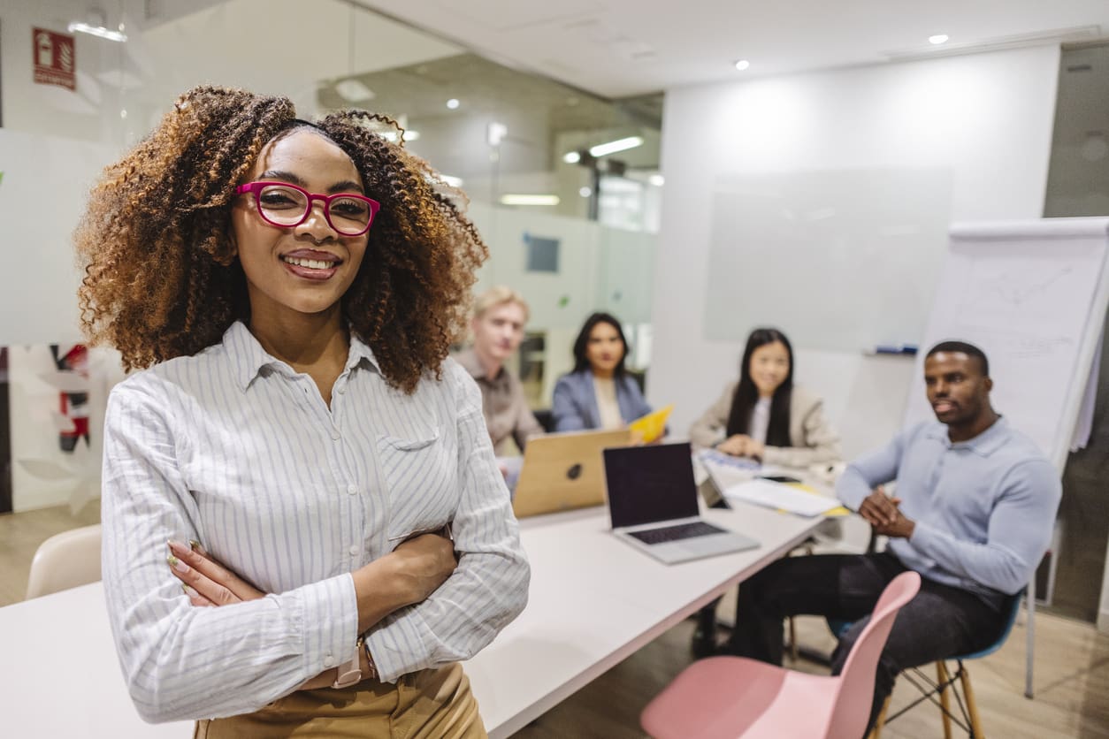 Confident businesswoman smiling with arms crossed during office meeting